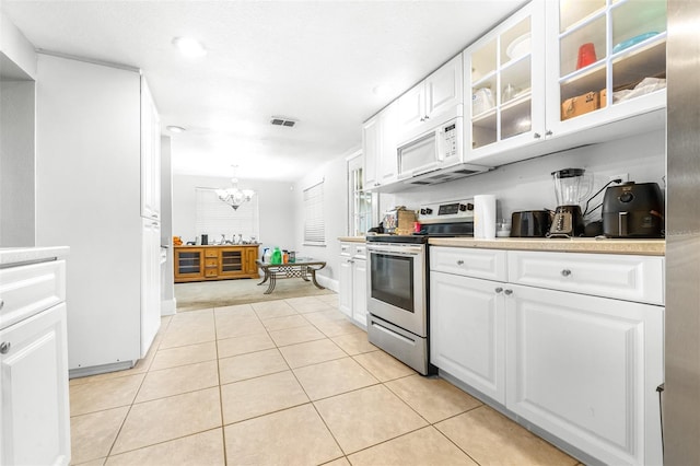 kitchen with hanging light fixtures, stainless steel range with electric cooktop, white cabinetry, and light tile patterned flooring