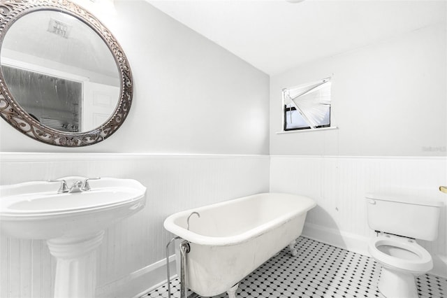 bathroom with toilet, vaulted ceiling, a tub, and sink