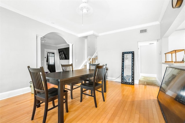 dining space featuring ornate columns, ornamental molding, and light hardwood / wood-style flooring