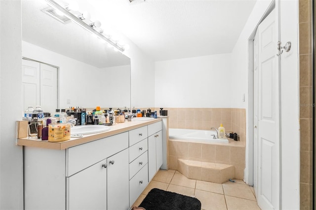 bathroom with tiled bath, vanity, and tile patterned flooring