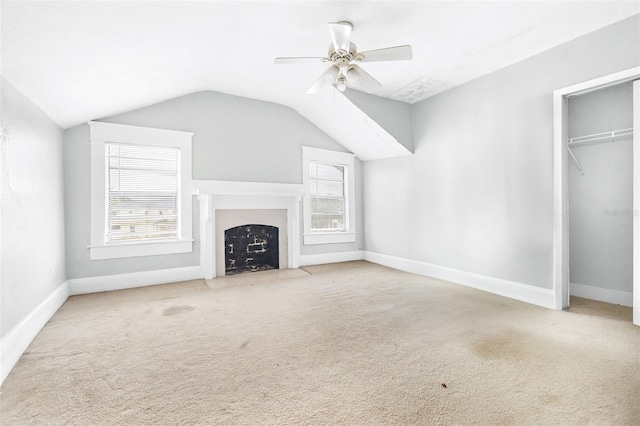 unfurnished living room with vaulted ceiling, ceiling fan, a wealth of natural light, and carpet