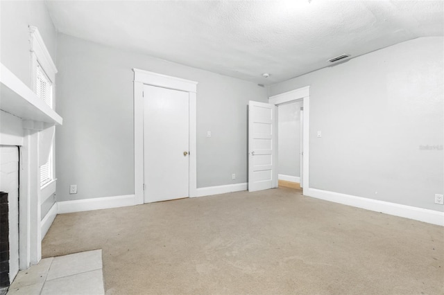 unfurnished living room featuring lofted ceiling, light colored carpet, a fireplace, and a textured ceiling