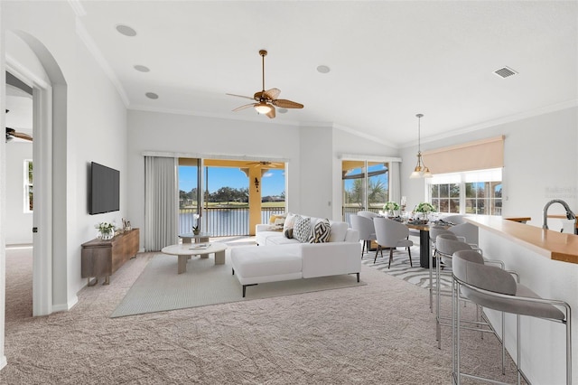 carpeted living room with a wealth of natural light, ornamental molding, and ceiling fan