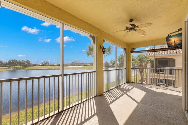 unfurnished sunroom featuring a water view, a healthy amount of sunlight, and ceiling fan