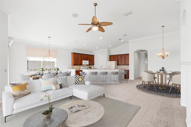 living room with vaulted ceiling, light colored carpet, ornamental molding, and ceiling fan with notable chandelier