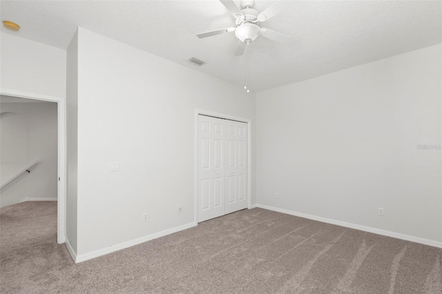 unfurnished room with a textured ceiling, light colored carpet, and ceiling fan