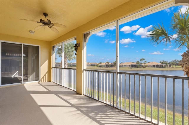 unfurnished sunroom with ceiling fan and a water view