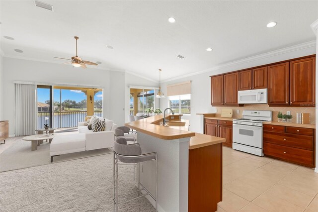 kitchen featuring decorative light fixtures, sink, backsplash, a water view, and white appliances