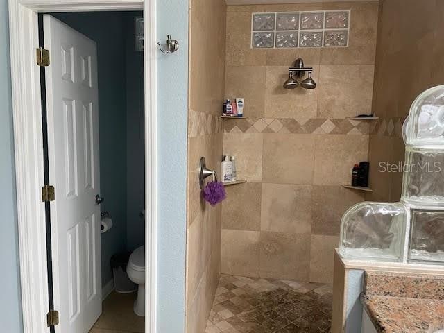 bathroom with tiled shower and toilet