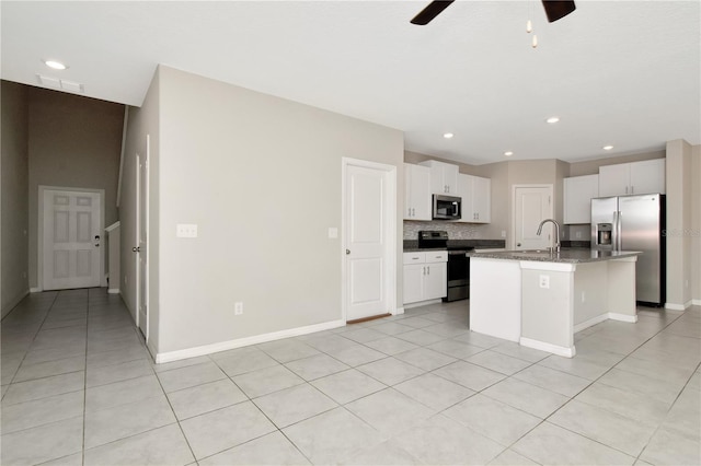 kitchen with light tile patterned flooring, an island with sink, white cabinetry, sink, and stainless steel appliances