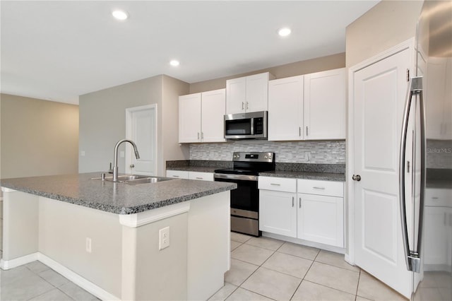 kitchen with sink, white cabinetry, tasteful backsplash, a center island with sink, and stainless steel appliances