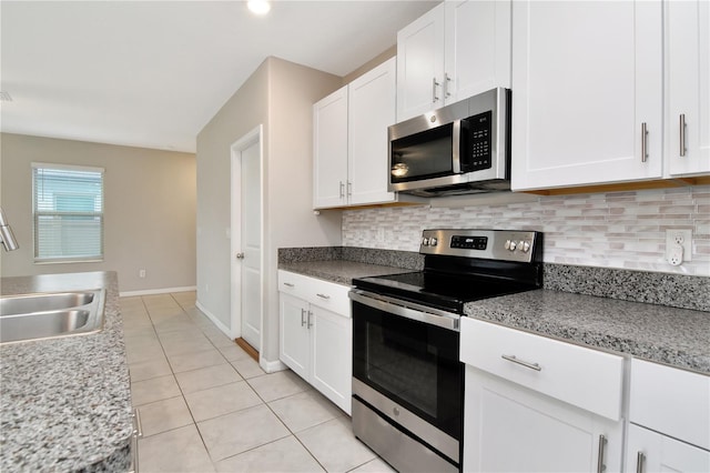 kitchen with light tile patterned floors, sink, backsplash, stainless steel appliances, and white cabinets