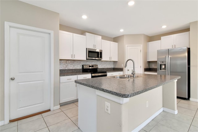 kitchen featuring appliances with stainless steel finishes, white cabinetry, an island with sink, sink, and backsplash