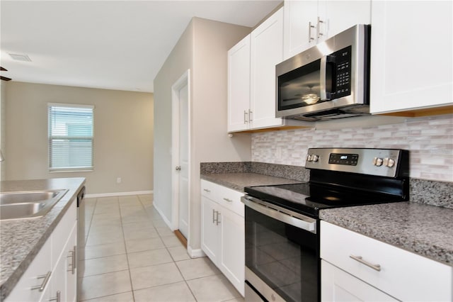 kitchen with light tile patterned floors, sink, backsplash, stainless steel appliances, and white cabinets