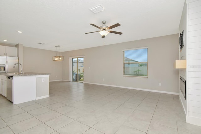 kitchen featuring stainless steel appliances, light stone counters, a large fireplace, white cabinets, and decorative light fixtures