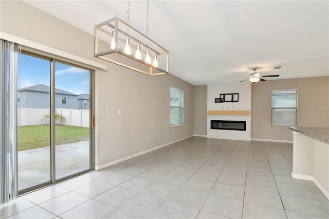 unfurnished living room featuring plenty of natural light, light tile patterned floors, and ceiling fan