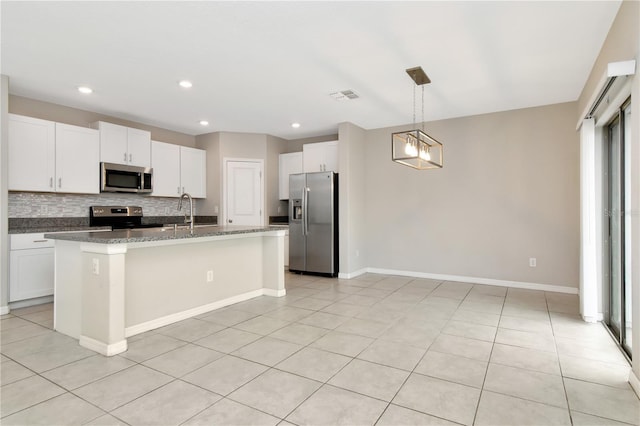 kitchen featuring white cabinets, an island with sink, appliances with stainless steel finishes, and backsplash