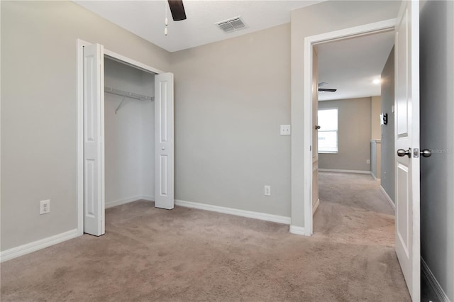 unfurnished bedroom featuring light carpet, a closet, and ceiling fan