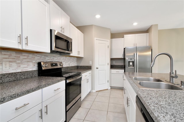 kitchen featuring appliances with stainless steel finishes, white cabinetry, a sink, and light tile patterned floors