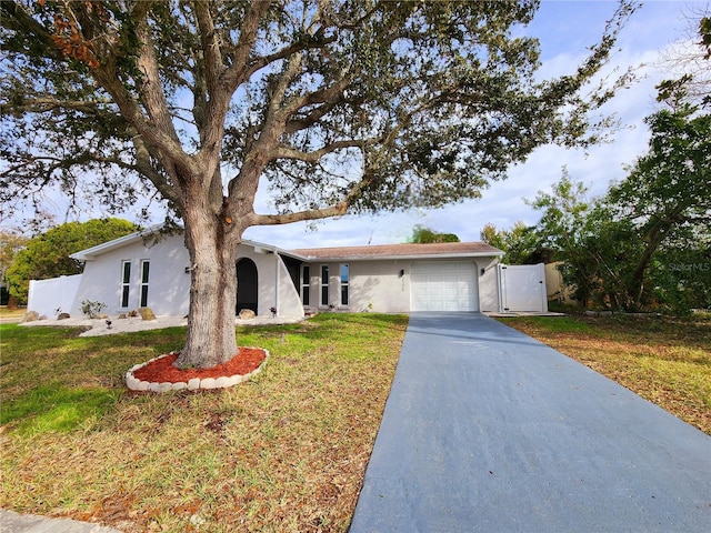 single story home featuring stucco siding, a front lawn, a gate, fence, and a garage