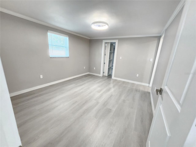 unfurnished bedroom featuring ornamental molding, a walk in closet, and light hardwood / wood-style floors