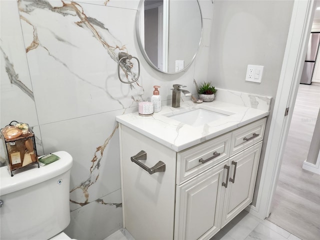 half bathroom featuring toilet, vanity, and marble finish floor