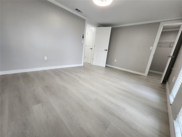 empty room with crown molding and light wood-type flooring