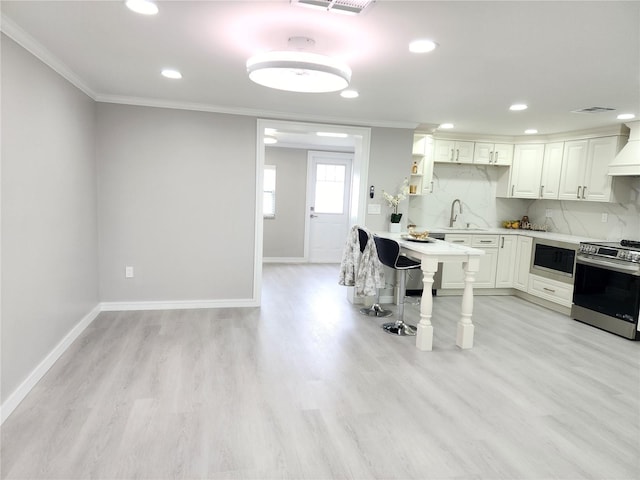 kitchen with built in microwave, stainless steel electric range oven, white cabinets, and backsplash