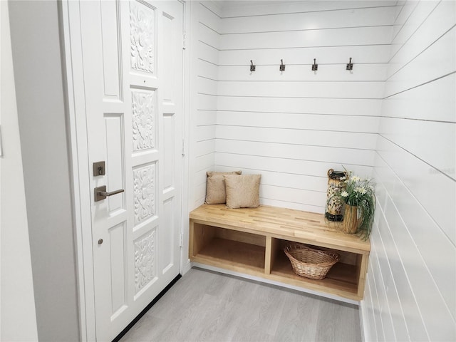 mudroom with light hardwood / wood-style floors and wood walls