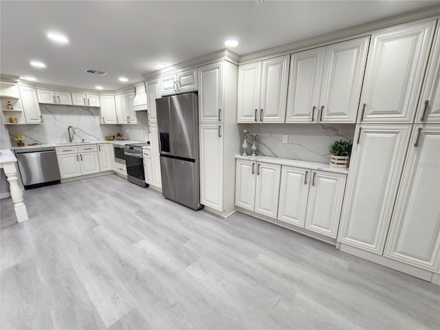 kitchen featuring white cabinetry, stainless steel appliances, sink, and light wood-type flooring