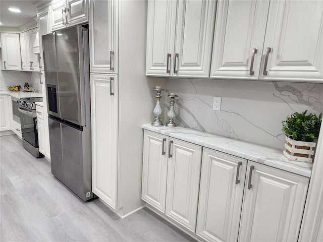 kitchen with light stone countertops, white cabinetry, appliances with stainless steel finishes, and light wood-type flooring