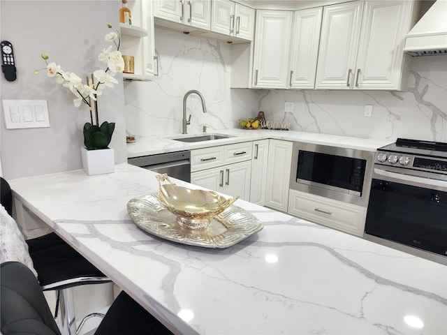 kitchen with sink, custom exhaust hood, tasteful backsplash, appliances with stainless steel finishes, and light stone countertops