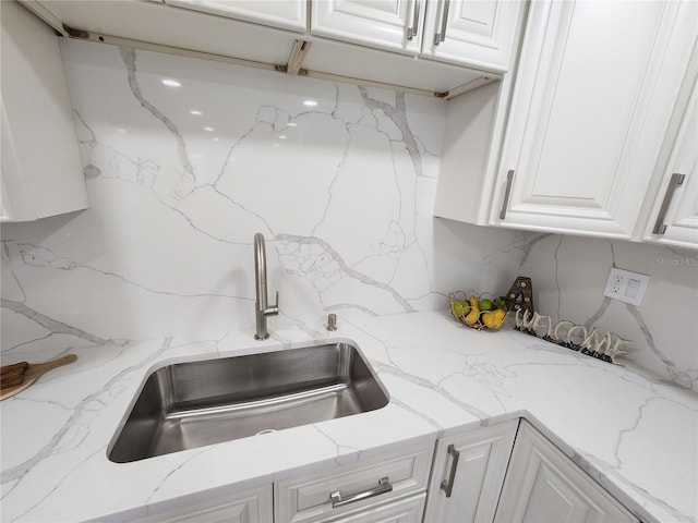 kitchen featuring tasteful backsplash, white cabinetry, and a sink