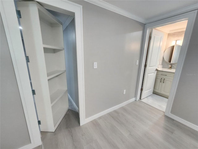 corridor with crown molding, baseboards, and light wood-type flooring