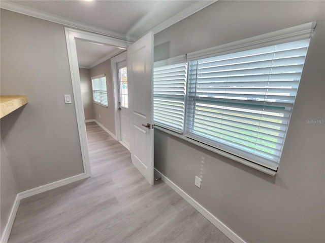 hallway with baseboards, light wood-style flooring, and crown molding