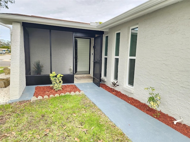 entrance to property featuring stucco siding and a yard