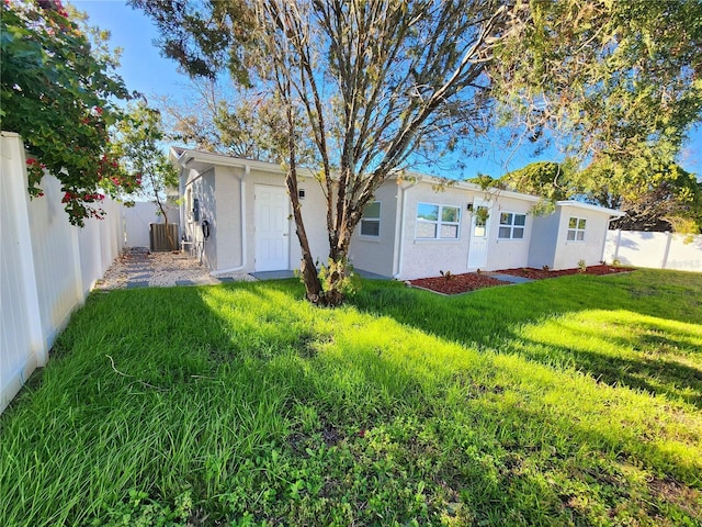 exterior space with central AC unit, a yard, fence private yard, and stucco siding