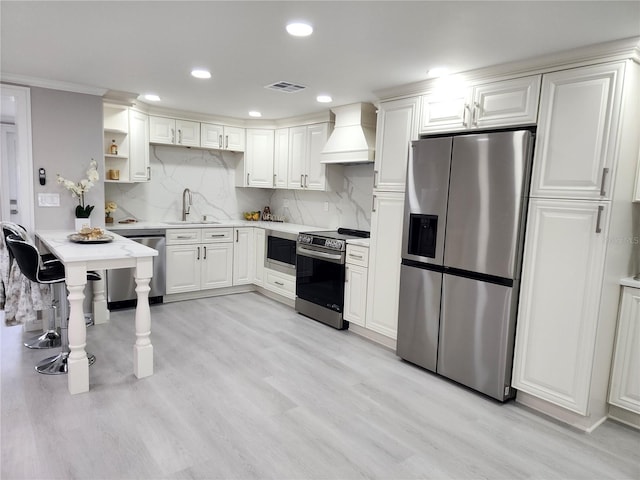 kitchen with premium range hood, light wood-style flooring, a sink, appliances with stainless steel finishes, and decorative backsplash