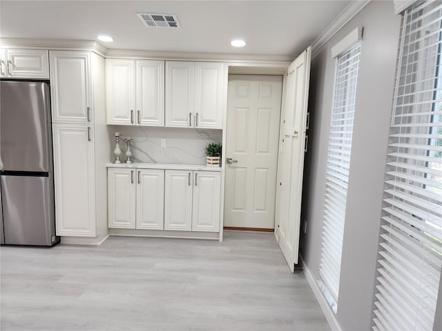 kitchen with white cabinetry, visible vents, freestanding refrigerator, and light wood-type flooring