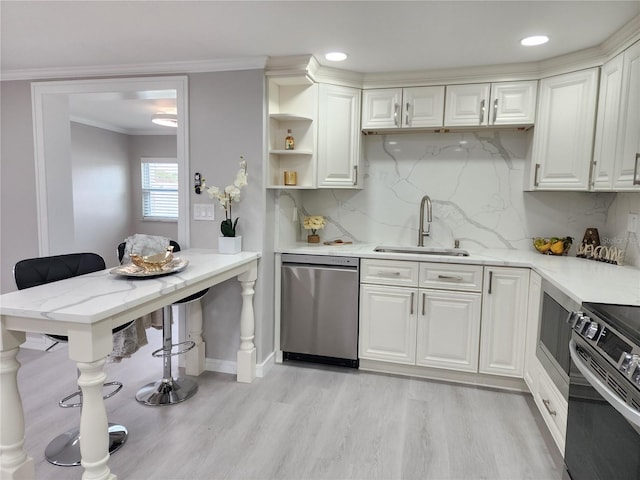 kitchen with light wood finished floors, a sink, stainless steel appliances, white cabinets, and crown molding