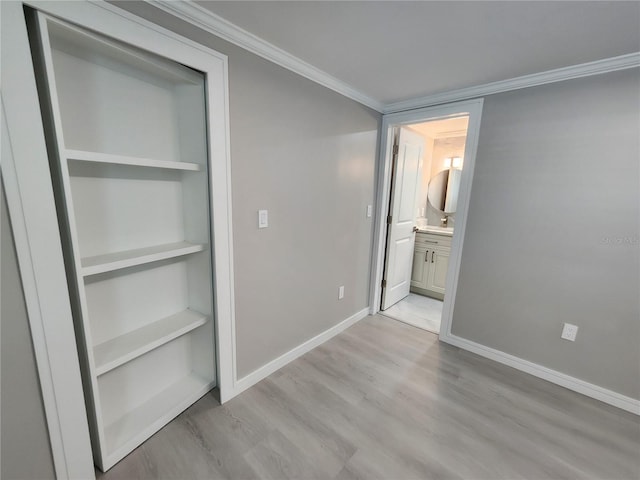 unfurnished bedroom with baseboards, light wood-style floors, ensuite bath, and ornamental molding