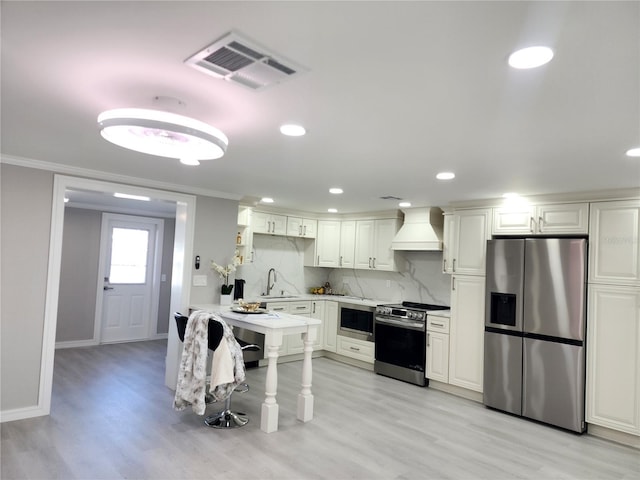 kitchen with visible vents, custom exhaust hood, a sink, appliances with stainless steel finishes, and tasteful backsplash