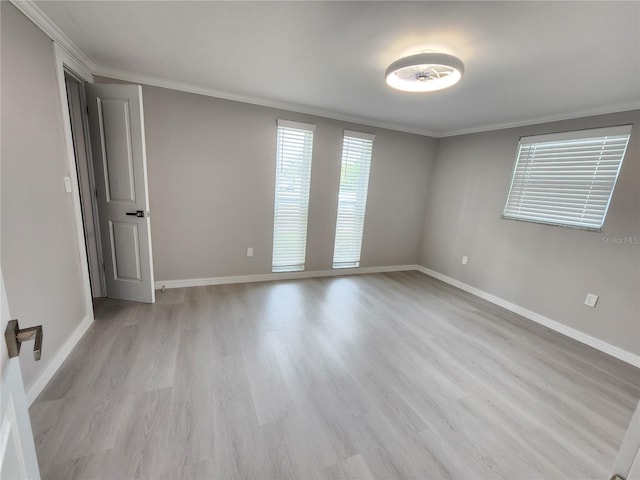 unfurnished room with baseboards, ornamental molding, and light wood finished floors