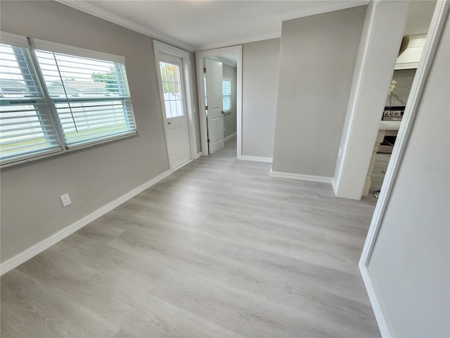 interior space with baseboards, crown molding, and light wood finished floors