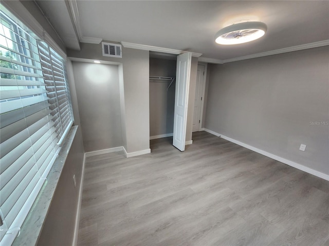 unfurnished bedroom featuring visible vents, baseboards, light wood-style floors, a closet, and crown molding