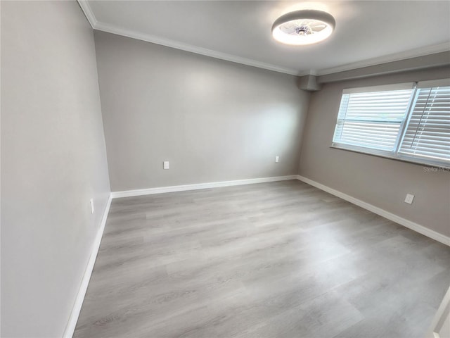 empty room featuring crown molding, baseboards, and wood finished floors