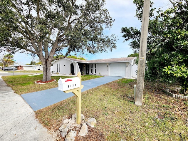 ranch-style house with stucco siding, driveway, a front yard, and a garage