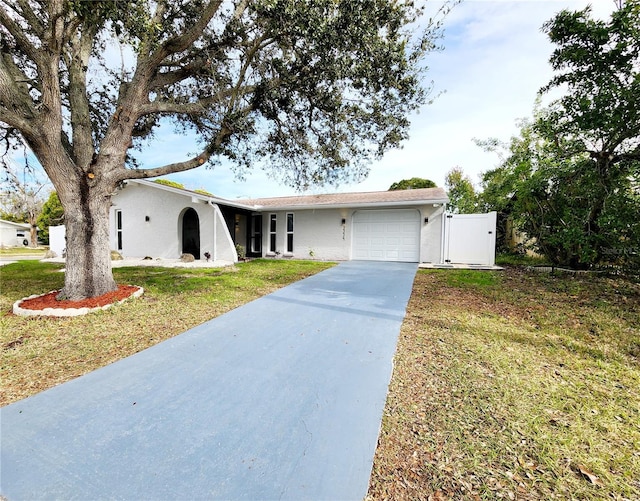 ranch-style house with stucco siding, a front lawn, a gate, concrete driveway, and a garage