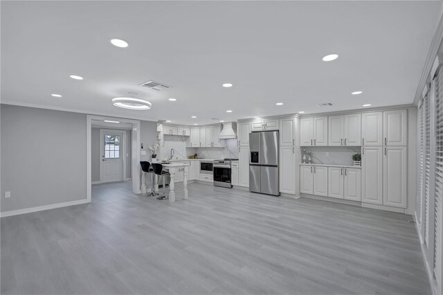 9334 Ledgestone Ln, Port Richey, FL 34668 - kitchen with light countertops, light wood finished floors, stainless steel appliances, custom range hood, and decorative backsplash
