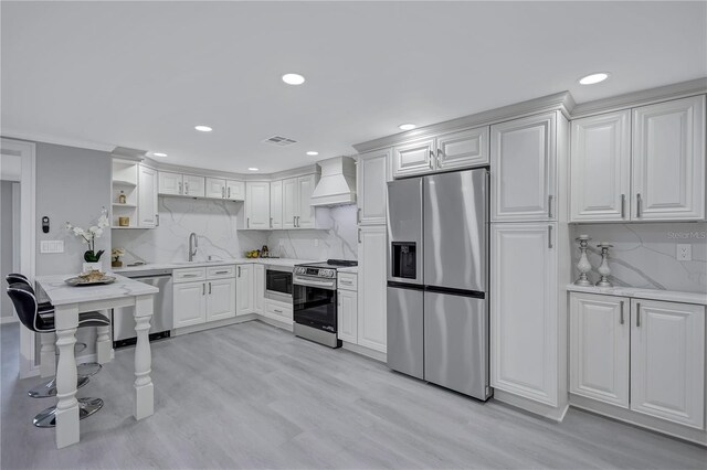 9334 Ledgestone Ln, Port Richey, FL 34668 - kitchen featuring custom range hood, light countertops, open shelves, light wood-style floors, and stainless steel appliances